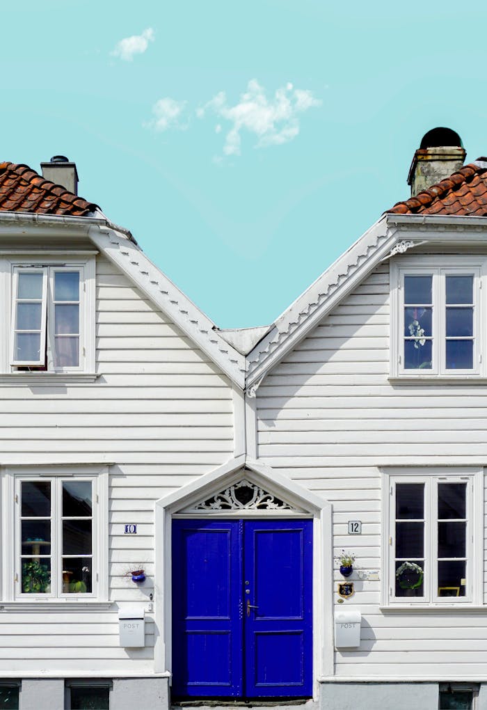 White wooden houses with blue doors under a bright sky in Stavanger, Norway. Classic Scandinavian architecture.