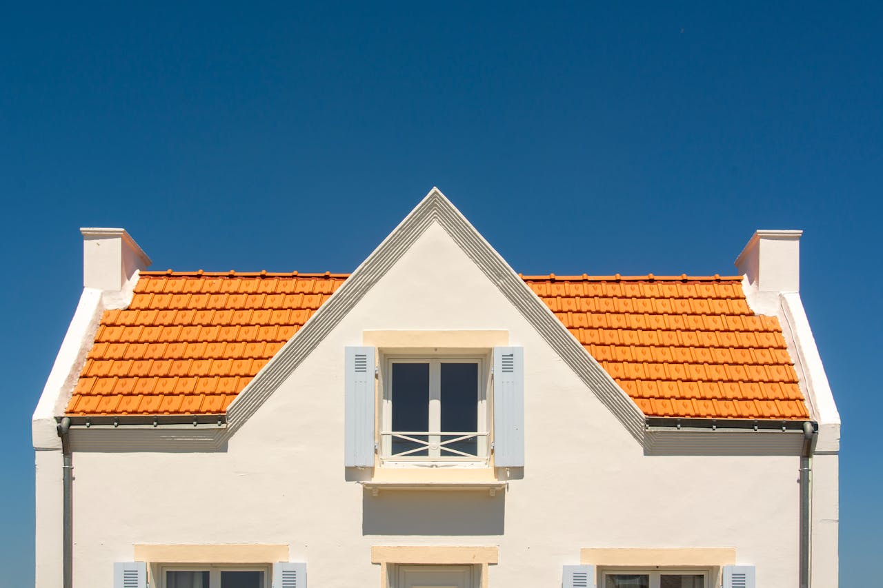 Front view of a house with orange tile roof and blue sky background.