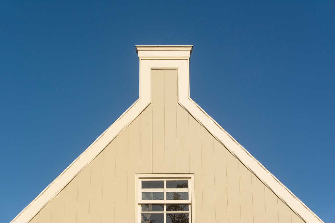 Triangular house facade against a clear blue sky, showcasing minimalist architecture.