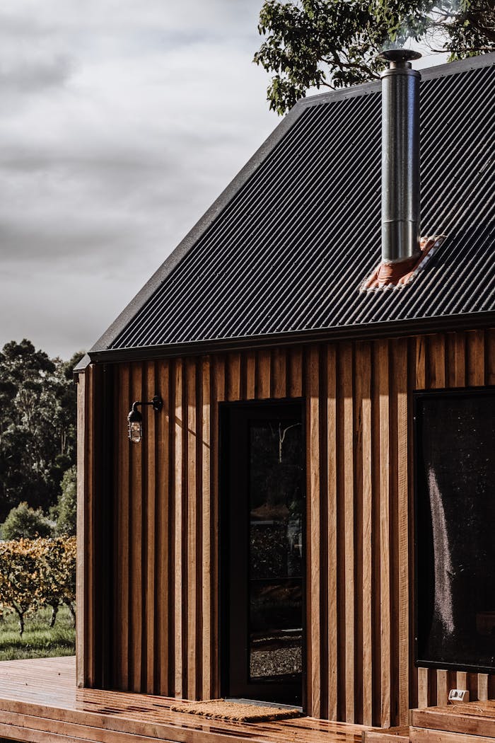Side view of a modern wooden cabin with minimalist design set in a natural landscape.